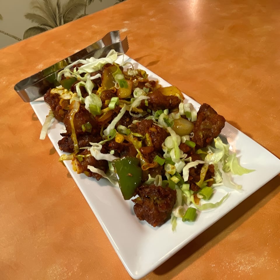 Indian Bistro's chili chicken, a vibrant dish with crispy chicken, bell peppers, and scallions.